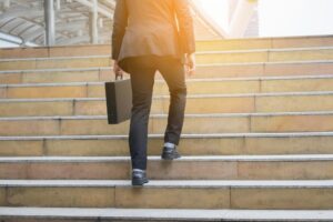 Business man walking up stair outdoor holding a brief case in hand